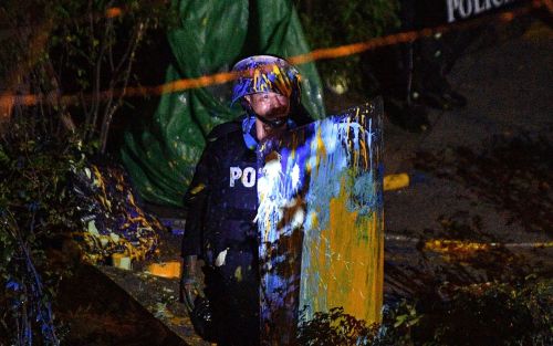 A policeman holds his riot shield after being splattered with paint by pro-democracy protesters duri