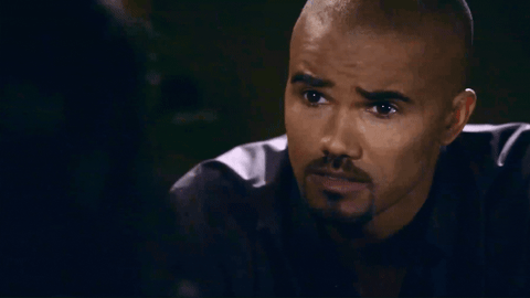 Derek Morgan, a man with a shaved head wearing a purple shirt, pulls away from Ellie slightly, his mouth opening and closing though he says nothing.