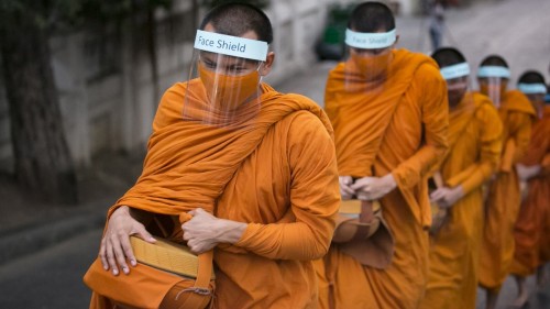 Buddhist monks wear face shields as they collect alms in Bangkok.> Photo: Allison Joyce.