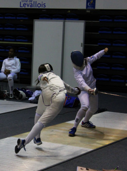 modernfencing:  en-un-instant:  flèche  [ID: an epee fencer parrying her opponent’s fleche.] 