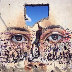 A child looking into the future. The graffiti is related to a mental health program in Gaza. The wall is part of a destroyed building from the last war. Photo by Wissam Nassar.