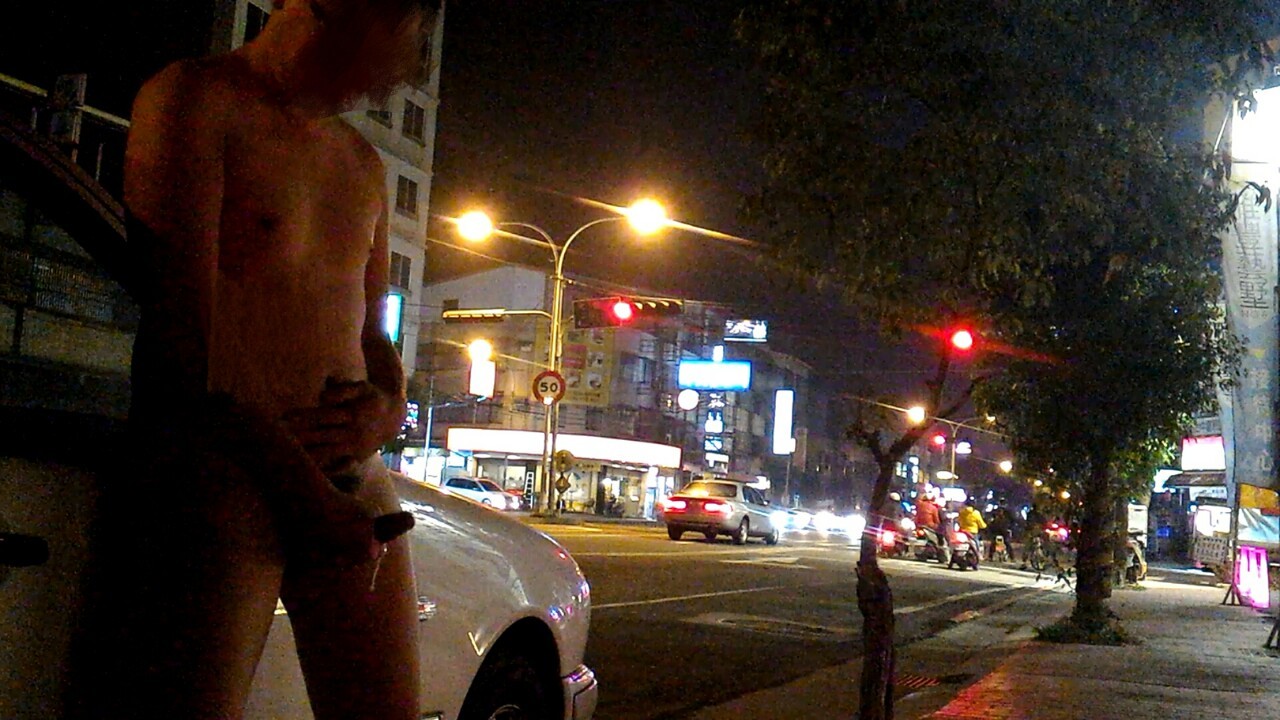 A naked Asian man shows off his hard cock, and masturbates, near a busy city intersection!