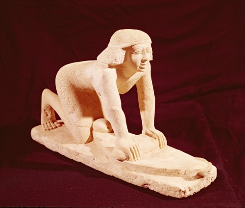 egypt-museum:Statue of a Woman Grinding GrainThe statue depicts a kneeling maid, who is leaning forw