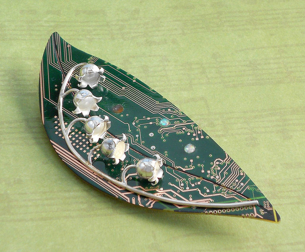 bluekraken:
“ Brooch with hand forged fine silver lily of the valey flowers on a sterling stem. The leaf is a polished and sealed circuit board inlaid with opals.
”