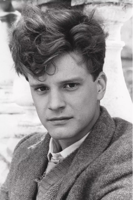 Young Colin Firth with poofy hair, wearing sweater vest and wood blazer
