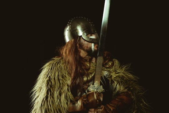 A man dressed in Early Middle Ages style furs and helmet holding a sword.