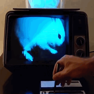 a gif of a cyan rabbit appearing in a tv screen. it lags before doing so.
