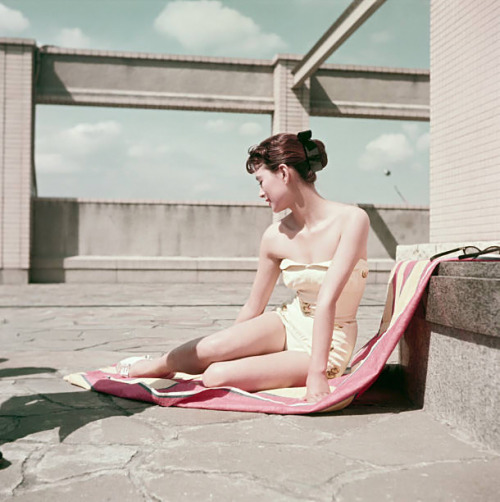 s-h-o-w-a:Japanese actress Mie Kitahara posing in a swimsuit sitting on a beach towel, Japan, late 1