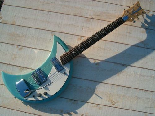 thepit:bleachedvi0let:Crucianelli Spazial 1965 Crecent Moon guitar 🌙[ID:4 pictures of an electric guitar taken from various angles. Its body is in the shape of a crescent. It’s light blue with a white pickguard. It has a vibrator arm/End ID]