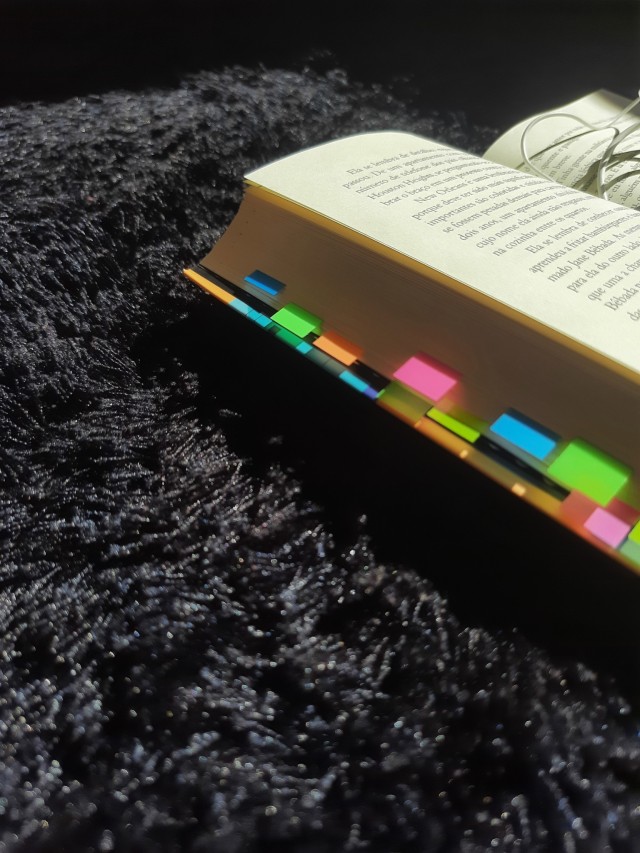 a close-up of one last stop with many colorful index tabs in the side open on the fluffy black rug.