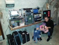gridcoin:Gridcoin user @dangermouse_77′s mining setup! Pictured here with his 2 children, and friend dragonfire - who built the electrical installation and some of the miners.