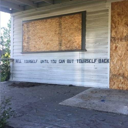 &ldquo;Sell yourself until you can buy yourself back&rdquo; Stencil spotted on an abandoned house in