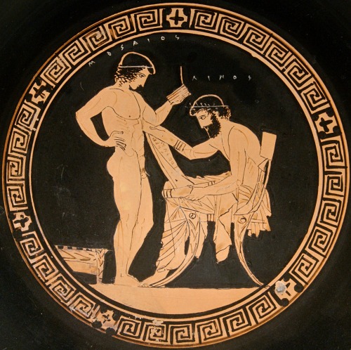 Scene from a palaestra.  A teacher, named Linos by the inscription, holds a papyrus roll; his pupil,