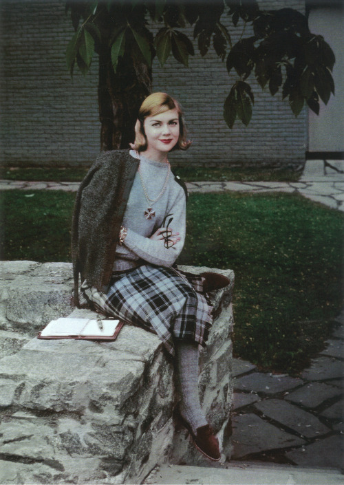 Model student, a member of Vassar&rsquo;s daisy chain, writing seated on a stone wall for Vogue,