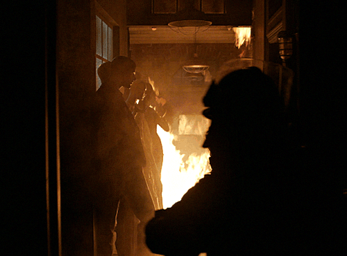 Athena in firefighter gear walking through a wall of fire