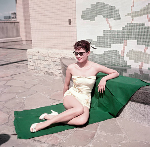 s-h-o-w-a:Japanese actress Mie Kitahara posing in a swimsuit sitting on a beach towel, Japan, late 1