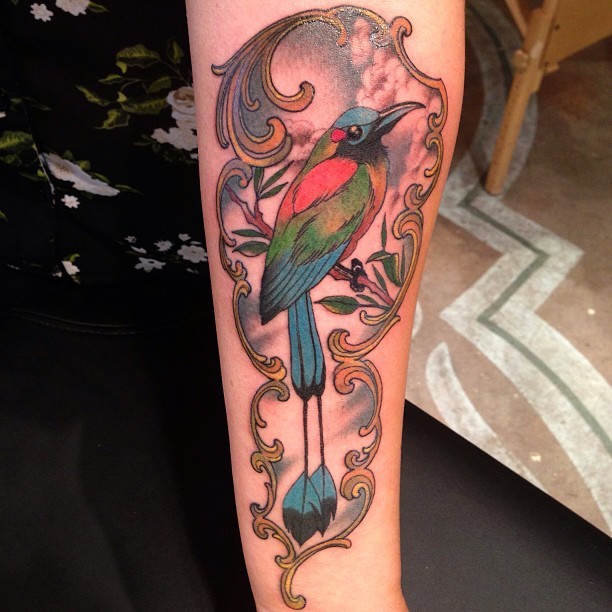 Colorful bird tattoo located on the shin