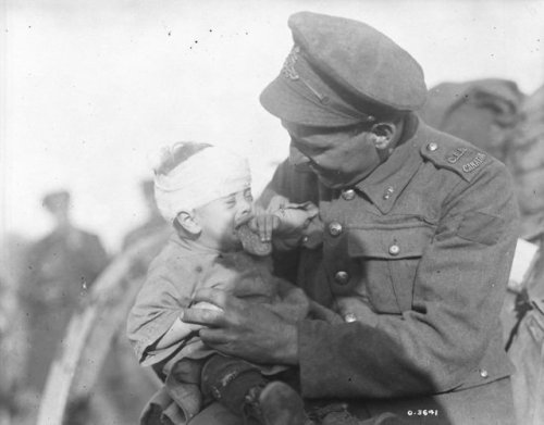 greatwar-1914:A Canadian soldier tries to comfort a little Belgian baby, who was hurt and whose moth