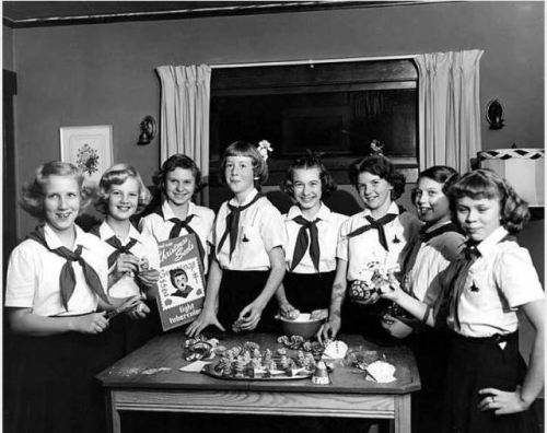 Campfire girls pose in front of table with ornaments made of pine cones, Christmas Seals Campaign, 1