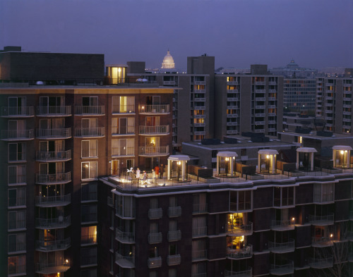 People gather on a roof terrace in the District of Columbia as lights come on in nearby buildings, A
