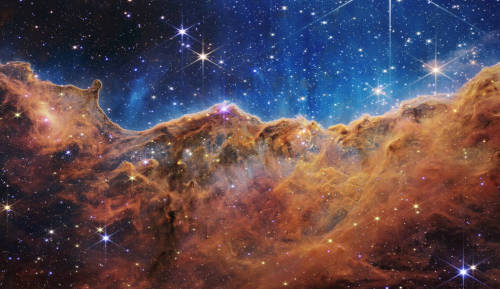 A photo of the Carina Nebula. It's orange and blue and speckled with stars.