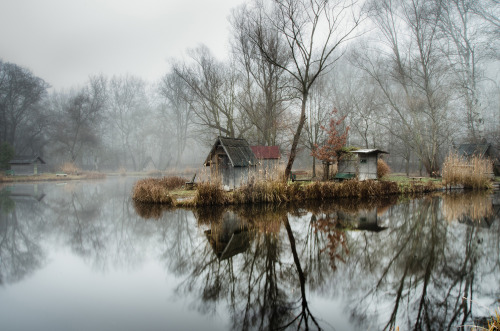 landscape-photo-graphy:Abandoned Fishing Village Outside of Budapest is Perfectly Reflected on the Lake by Viktor Egyed A few miles outside of Budapest lays a small abandoned fishing village composed of rustic huts, tall trees and an obscure atmosphere.