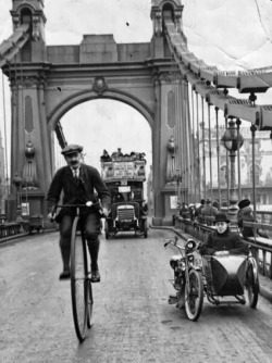 intimesgonebyblog:  A cyclist riding a penny farthing over Hammersmith Bridge, London. 