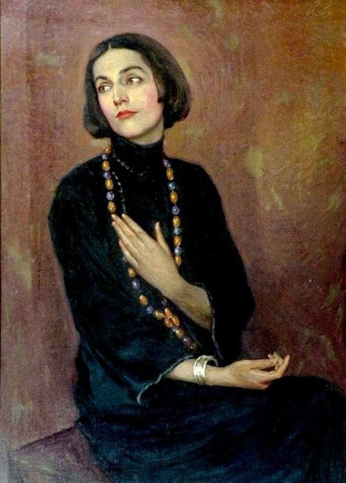 Portrait of Isadora Duncan wearing a blue dress and coloured bead necklace, three quarter length (19
