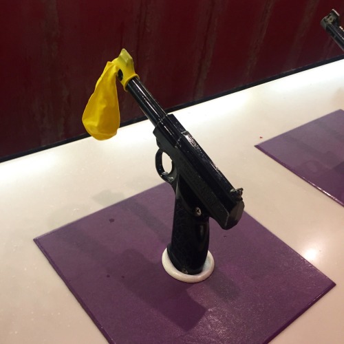 a yellow balloon, a black plastic gun, a purple square