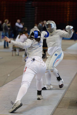 modernfencing:  [ID: two sabre fencers in a bout. The fencer on the left is lunging as her opponent tries to parry and retreat.] Azza Besbes (left) against Alizée Jammes, at the Tournoi international Paris Île-de-France 2013! Photo by Marie-Lan Nguyen.