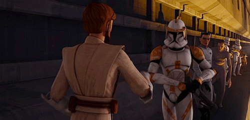 Obi-Wan, back to the camera, offers an approaching Cody a hand. Cody grasps his hand and Obi-Wan helps him jump down to a lower level. Behind Cody is a queue of other clones.