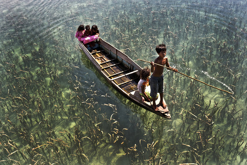  Children ride on a boat on the crystal clear adult photos