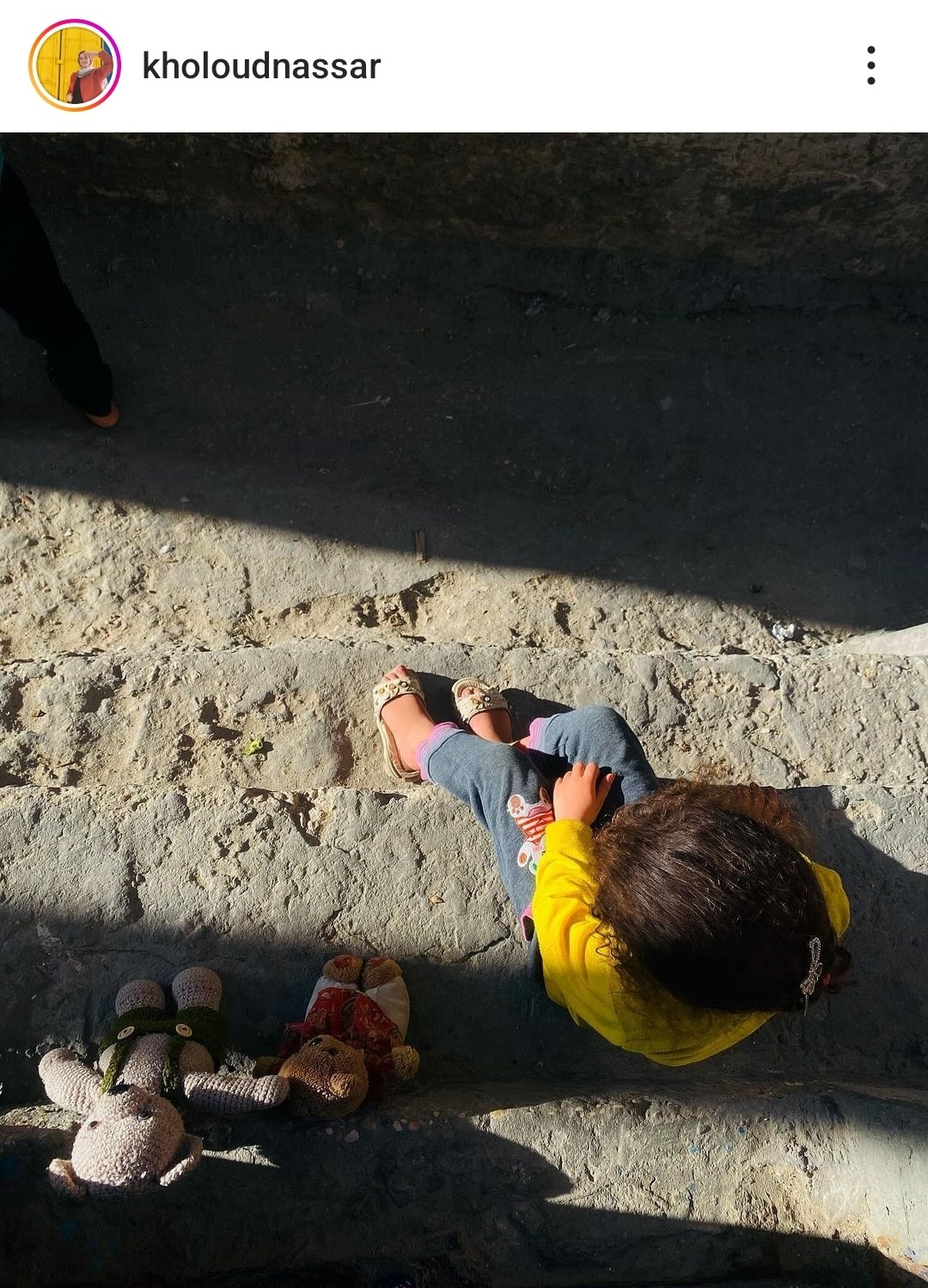 An overhead shot of a small child sitting on the ground, exhausted.
