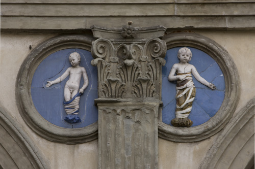 Glazed blue terracotta roundels with reliefs of “bambini” were created by Andrea della Robbia to fit