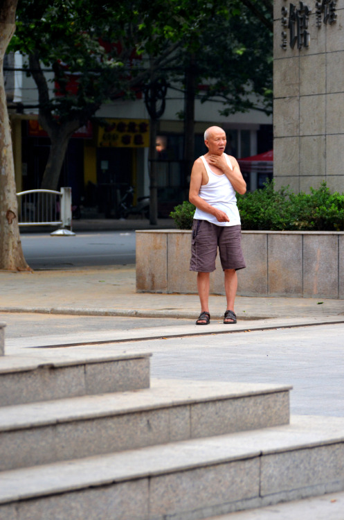 An old man stands at the gates of the art museum in Zhengzhou, China.