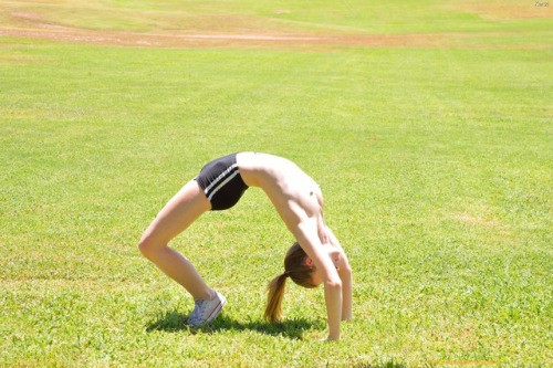 one-legged girl makes a bridge stand on the grass