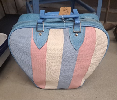 a vintage bowling bag in light blue, with alternating stripes of light blue, pink, and white. it looks a bit like the trans pride flag.