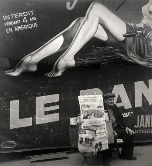 Jambes de l’affiche (Vendeur de journaux devant une affiche de cinéma où figure les jambes de l’héroïne d’un film, Place