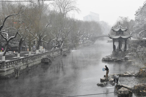 A man takes water from a moat as snow turns the city into a winter wonderland in Jinan, China on Jan