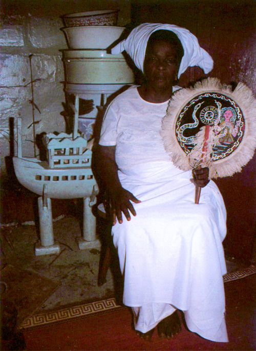 ukpuru: [Mami Wata priestess Mrs. Margaret Ekwebelam] seated in an aquamarine-colored shrine room an