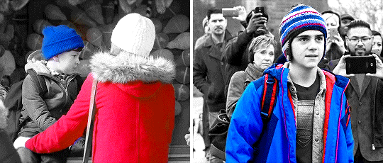 Two side-by-side gifs. They are black and white except for two colours. On the right, Marilyn and toddler Billy are seen. Marilyn is wearing a bright red coat and Billy a bright blue hat. Ten years later, Marilyn opens the door to Billy, wearing a bright red polo shirt. Inside the apartment, one glimpses the red coat from the carnival. On the left, Freddy is shown in the outfit he wears the most in the movie. His coat has a bright red inner lining, and there are red highlights in his backpack and hat. The rest of his coat and hat are bright blue, his outfit combining bright blues and reds, with red being Billy's signature colour in his Shazam-form and blue being Freddy's. 