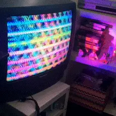the camera pans around an old tv with rainbow static-like imagery on it