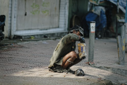 A homeless man eats some leftover bread. Bandung, Indonesia