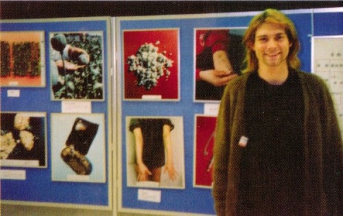youremyvitamins:Kurt Cobain, Japan, February 1992 - At the Tokyo airport custom’s gate, Kurt found it humorous to have Courtney photograph him in front of pictures of illegal drugs. 