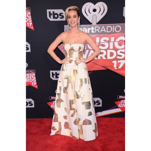 Katy is wearing an August Getty Atelier jumpsuit, Jimmy Choo shoes, Jacob &amp; Co earrings and 