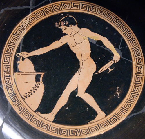 A youth, serving as cup-bearer at a symposium, draws wine from a krater (mixing-bowl) with an oinoch