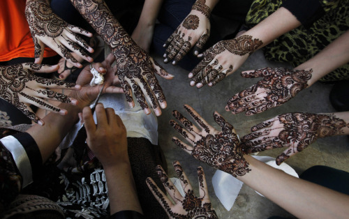 A Pakistani beautician paints the hands of customers with henna in Karachi, Pakistan on July 27, 201