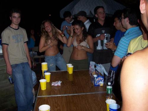 Two girls playing backyard strip beer pong, both end up topless as a result.