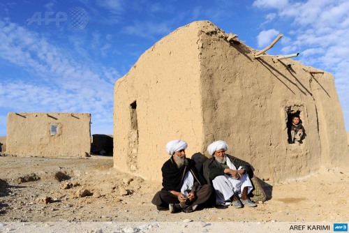 Afghan residents sit outside a hut on the outskirts of Herat on February 12, 2014. Some nine million