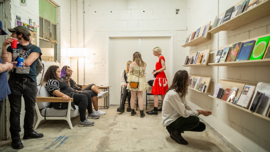 People engaging in conversation and looking at a shelf of publications